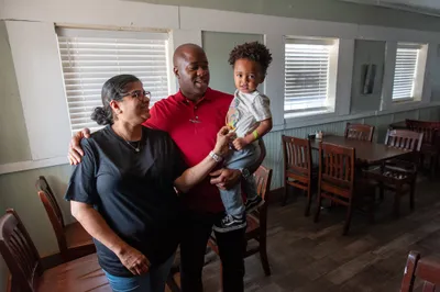 Sheba Smith, left, and Milko Smith, hold their grandson, Carti, at their family restaurant in Hope, Ark. on Sept. 7, 2023. Photo by Rory Doyle.